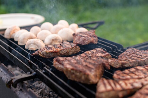 Saftige Fleischstücke und Champignons werden auf einem Grill geröstet