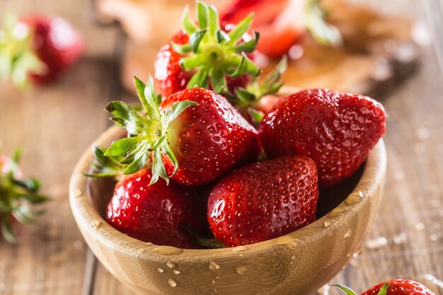 Saftige gewaschene Erdbeeren in Holzschale auf Küchentisch.