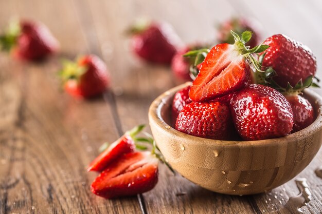 Saftige gewaschene Erdbeeren in Holzschale auf Küchentisch.