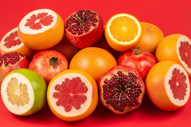 Saftige Grapefruit, Orange, Granatapfel, Zitrus Sweetie auf rotem Grund.