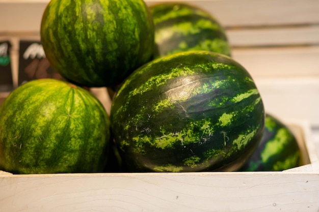 Saftige grüne Wassermelone auf dem Markt. Verkauf von Früchten auf dem Markt in einer Holzkiste. Foto für Anzeige