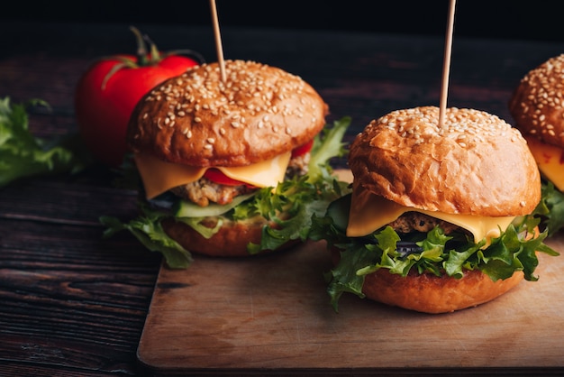 Saftige hausgemachte Hamburger mit Fleisch, Käse, Salat, Tomaten auf einem Brett