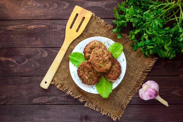 Saftige hausgemachte Schnitzel (Rindfleisch, Schweinefleisch, Huhn) auf einem hölzernen Hintergrund. Für einen Hamburger. Die Draufsicht.