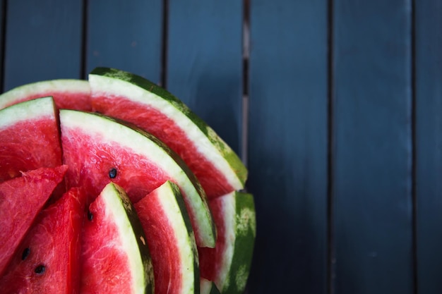 Saftige leuchtend rote Stücke geschnittener Wassermelone auf schwarzem Tischhintergrund