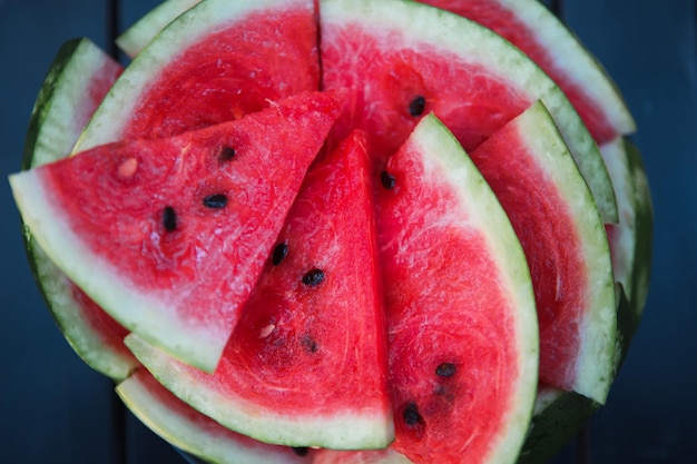 Saftige leuchtend rote Stücke geschnittener Wassermelone auf schwarzem Tischhintergrund