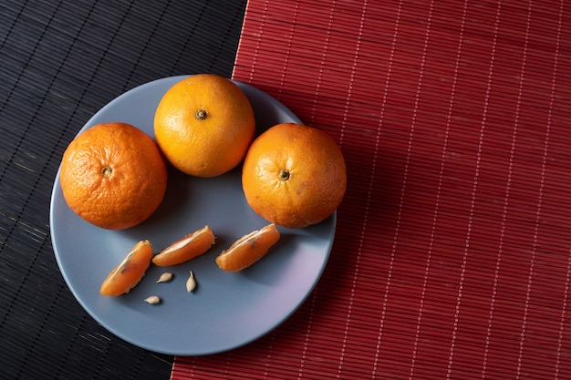 Foto saftige orange mandarinen und scheiben in teller auf einem schwarzen mit rotem stil tisch