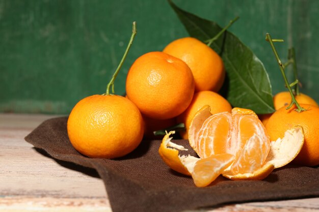 Saftige reife Mandarinen mit Blättern auf Holztisch