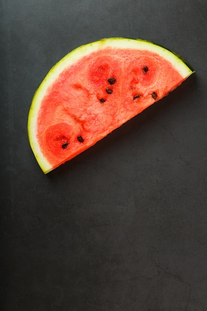 Saftige Scheibe der roten Wassermelone auf Steinschwarzem