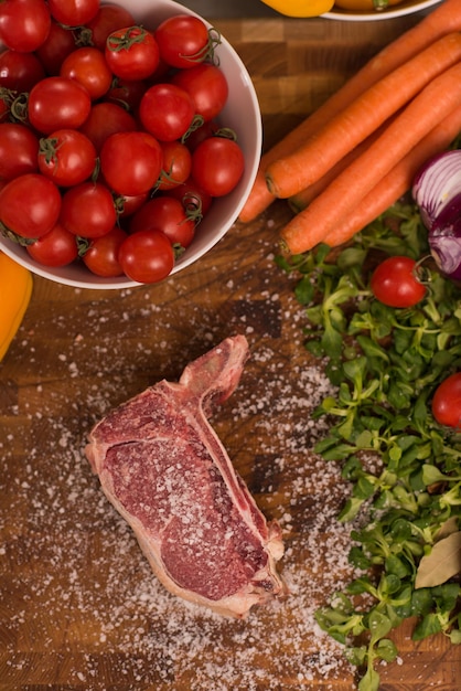 Saftige Scheibe rohes Steak mit Gemüse auf einem Holztisch