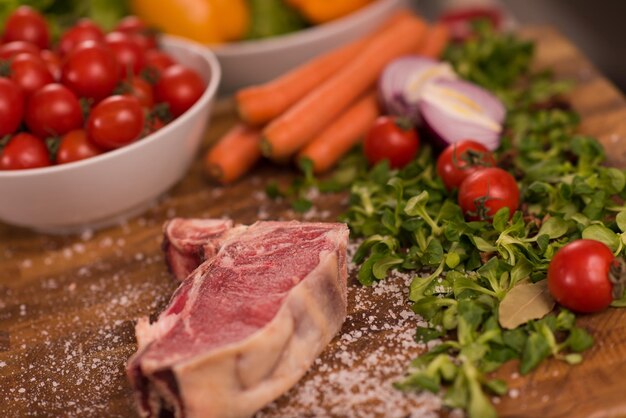 Saftige Scheibe rohes Steak mit Gemüse auf einem Holztisch