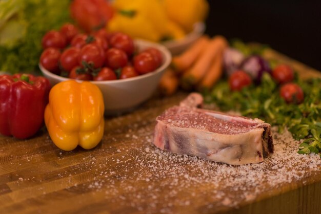 Saftige Scheibe rohes Steak mit Gemüse auf einem Holztisch