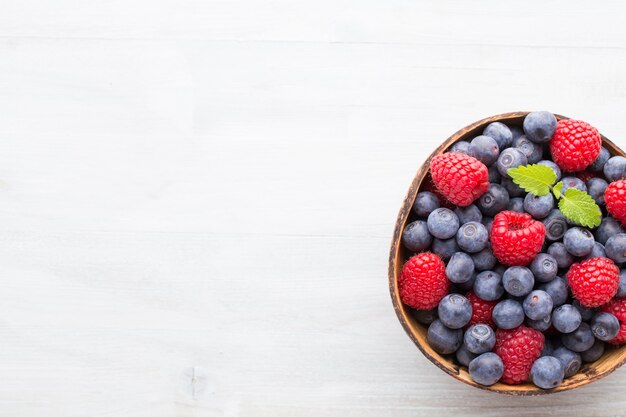 Saftige und frische Blaubeeren mit grüner Minze auf rustikalem blauem Tisch