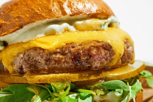 Saftiger Burger mit Käse und Rucola auf weißem Hintergrund Hartes Licht