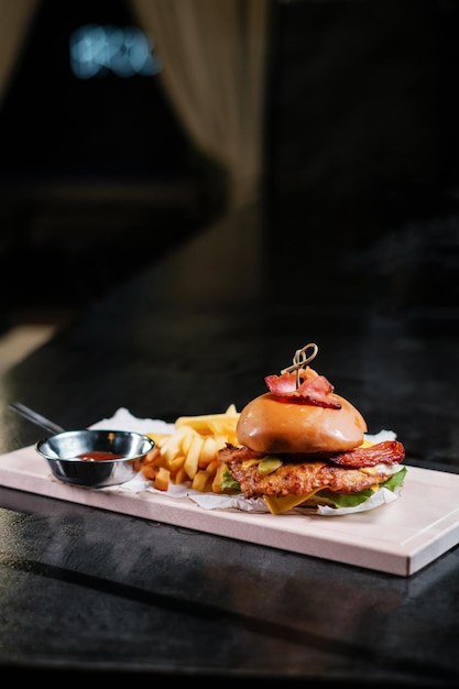 Saftiger Burger mit Pommes auf Holzbrett