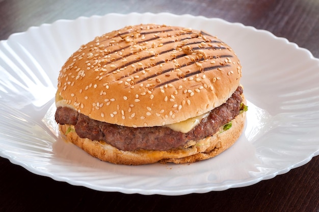 Saftiger Cheeseburger mit Käse auf einem weißen Teller