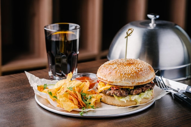 Saftiger Cheeseburger mit Kartoffelchips und Cola