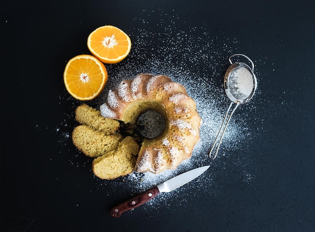 Saftiger Orangen-Joghurt-Kuchen mit Zuckerpulver auf dunklem Grunge-Hintergrund