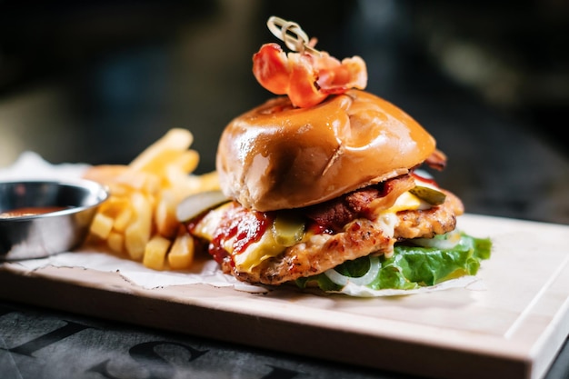 Saftiger Speckburger mit Pommes und Ketchup auf Holzbrett