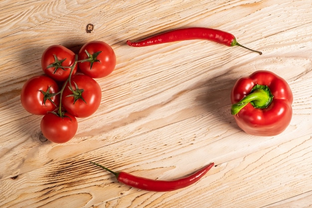 Saftiges Gemüse, Paprika und Chilischoten und Tomaten auf einem Holztisch.