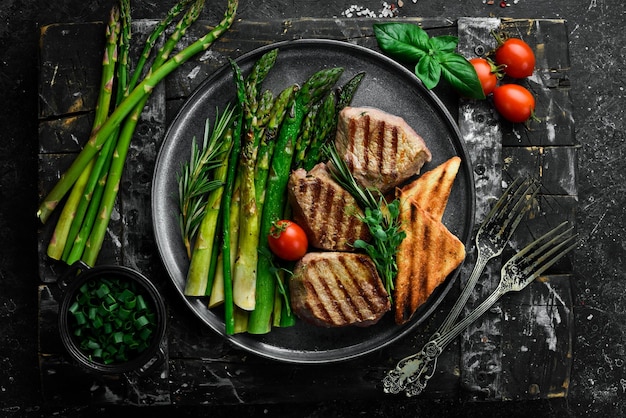 Saftiges Kalbssteak mit Spargeltomaten und Toast auf schwarzem Steinhintergrund Top