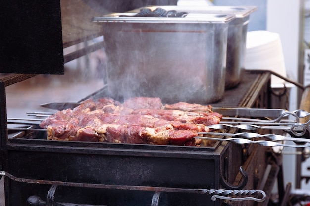 Saftiges mariniertes Fleisch wird gegrillt oder gegrillt oder gebrannt. Fleischstücke am Spieß aufgereiht. Der Prozess der Herstellung von Fleischspieß auf Holzkohle. Grill im Garten