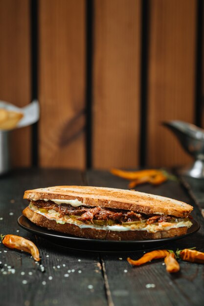 Saftiges Ochsenschwanz-Sandwich auf einem dunklen Holztisch