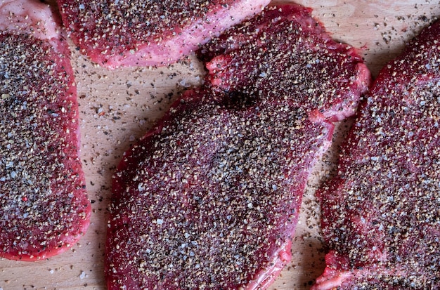 Saftiges Pfeffersteak mit schwarzem, rotem, grünem Pfeffer auf einem Holztisch Kochen von mittelgeröstetem Pfeffersteak