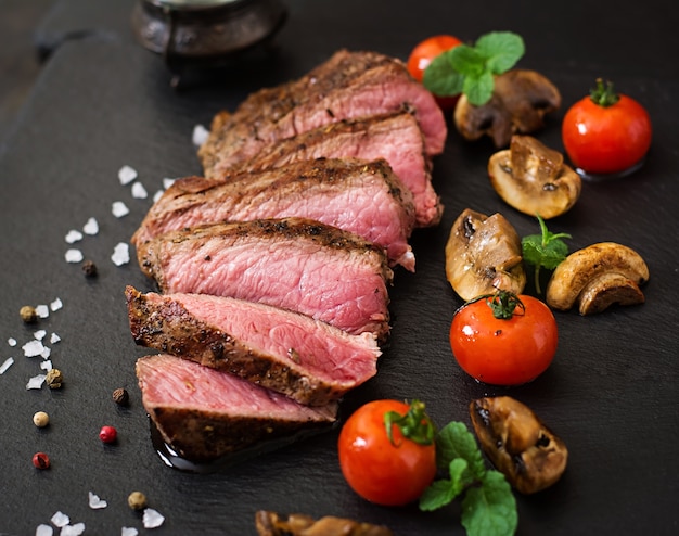 Saftiges Steak mittleres seltenes Rindfleisch mit Gewürzen und gegrilltem Gemüse.