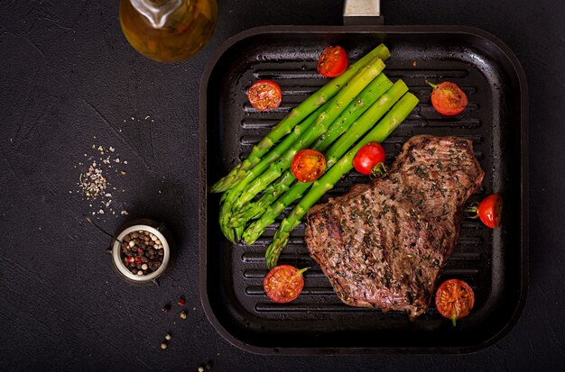 Saftiges Steak seltenes Rindfleisch mit Gewürzen auf einem Holzbrett und Spargelgarnitur. Flach liegen. Draufsicht