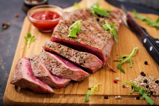 Saftiges Steak seltenes Rindfleisch mit Gewürzen auf einem Holzbrett