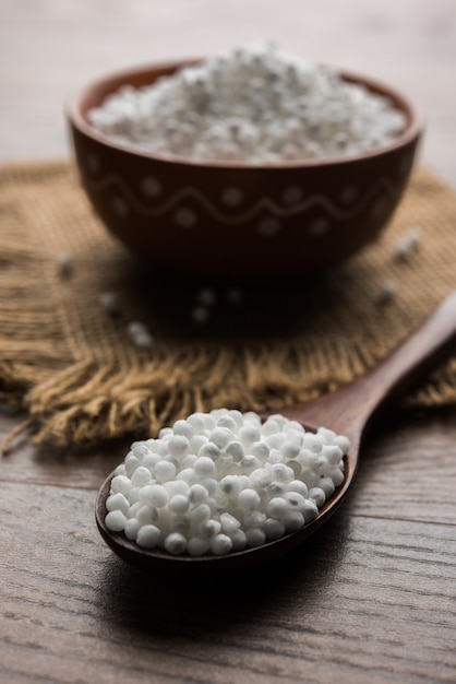 Sago oder Sabudana serviert in einer Schüssel oder als Haufen mit Holzlöffel über stimmungsvollem Hintergrund. selektiver Fokus