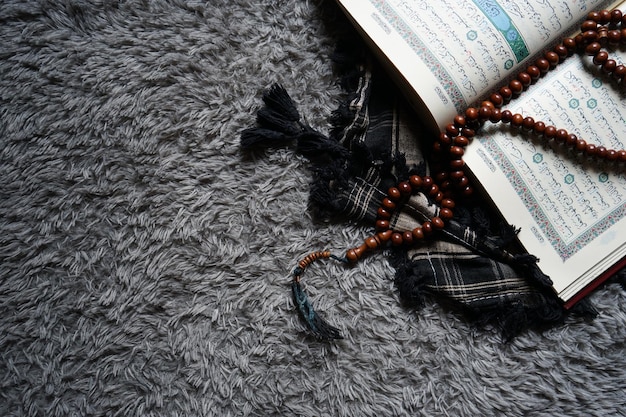 Foto el sagrado al quran con caligrafía árabe escrita. al quran y cuentas de rosario o tasbih