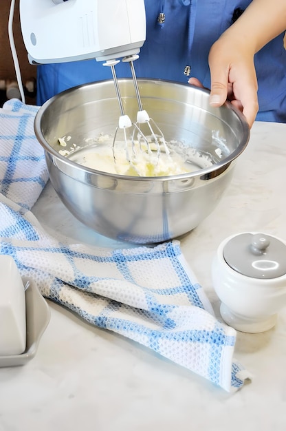 Sahne wird mit einem Mixer in einer Schüssel auf dem Tisch geschlagen und es gibt ein Handtuch