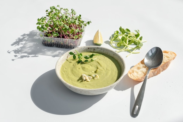 Sahnesuppe mit Blauschimmelkäse, Brot und Microgreens auf weißem Hintergrund. Sauberes Essen, Diät, Entgiftungs-Lebensmittelkonzept.