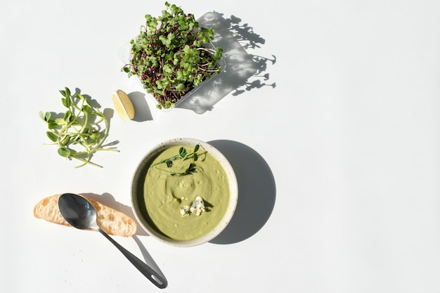 Foto sahnesuppe mit blauschimmelkäse, brot und microgreens auf weißem hintergrund. sauberes essen, diät, entgiftungs-lebensmittelkonzept.