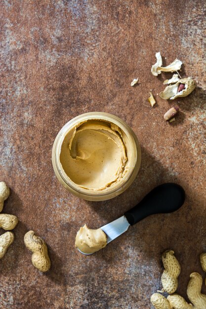 Sahnige Erdnussbutter und Messer auf Draufsicht der rostigen Oberfläche