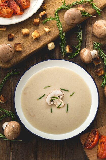 Sahnige Pilzsuppe auf Holz mit Champignonpilzen