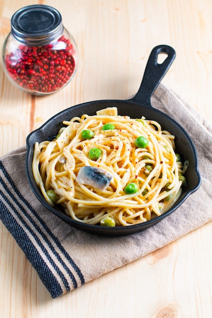 Sahnige weiße Soße der Lebensmittelkonzept-Spaghettis in der Gusseisenbratpfanne auf hölzernem Hintergrund