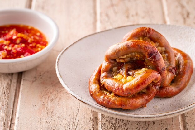 Sai Moo Yang, comida tailandesa, intestinos de cerdo a la parrilla con salsa picante sobre fondo de textura de madera blanca vieja, despojos, desplume, carnes de órganos