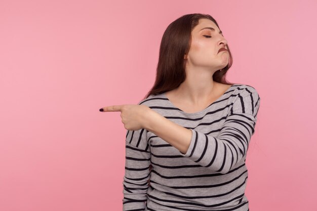 Saia retrato de mulher irritada vexada em moletom listrado fazendo caretas loucamente e ordenando ir embora sentindo-se traído ressentido rompimento conceito tiro de estúdio interior isolado no fundo rosa