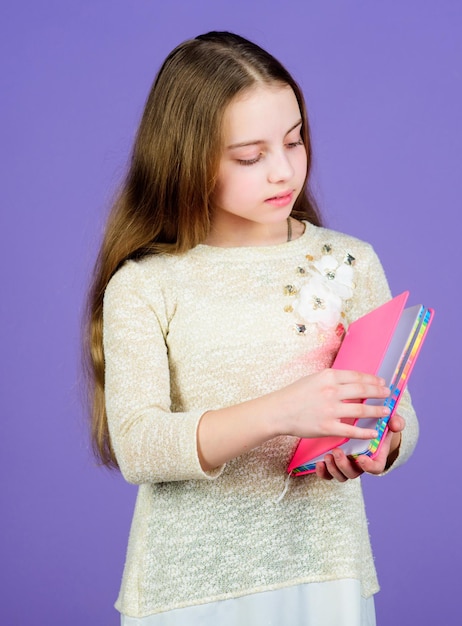 Saiba mais A menina segura o fundo violeta do livro Criança mostra o bloco de notas do livro Conceito do livro Literatura infantil Desenvolvimento e educação Habilidade de leitura Diário pessoal Planejador do bloco de notas Artigos de papelaria da escola