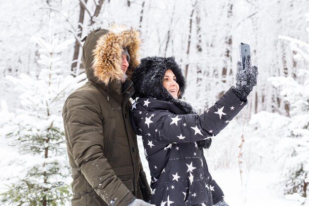 Saison- und Beziehungskonzept lustiges Paar, das im Winter Selfie macht