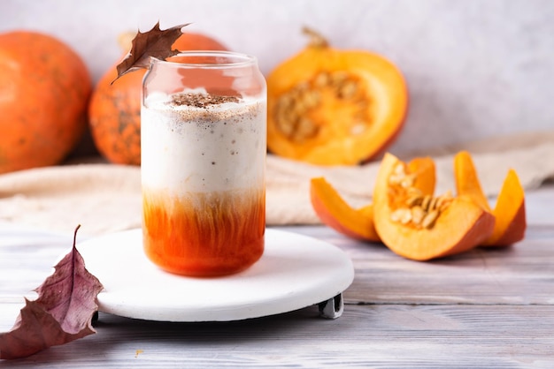 Saisonale Kürbisgewürzlatte in einem Glas auf weißem Hintergrund, gesundes Kaffeegetränk mit Schlagsahne.