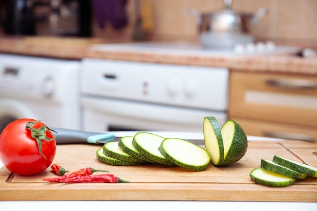 Saisonale Zucchini- oder Zucchinischeiben auf einem Holzbrett. Gemüse für den Grill vorbereiten, für das Restaurant. Küchenhintergrund, Lebensmittelhintergrund. gesunde vegane Ernährung oder vegetarisches Essen.