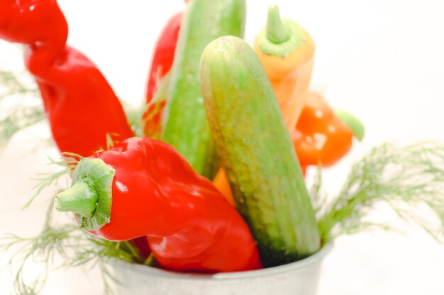 Saisonales Gemüse und Obst, Pfeffer, Gurke und ein Bündel frischer Dill in einem Zinkbecher