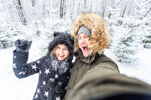Saisonliebe Technologie und Freizeitkonzept glückliches Paar, das im Winter ein Selfie mit dem Smartphone macht