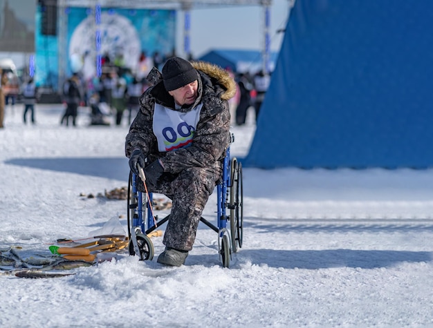 Foto sakhalin rússia 26022022 pessoa com deficiência sentada em uma cadeira de rodas pegando peixe no gelo