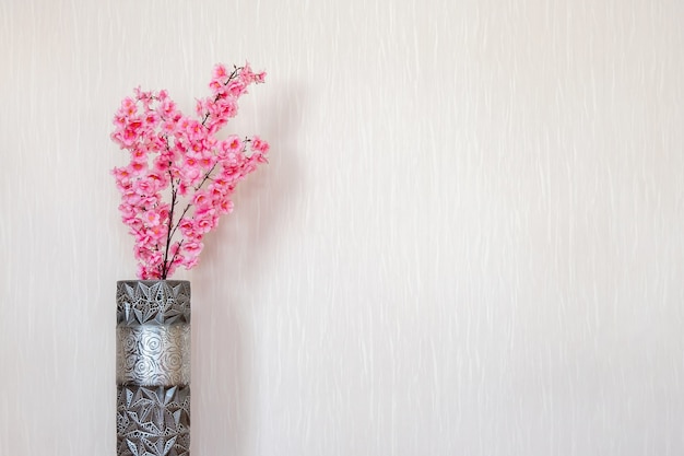 Sakura rosa en un jarrón en el interior contra la pared blanca