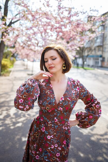 Sakura se ramifica com flores em uma árvore nas ruas da cidade. Garota de mulher feliz girando na rua com sakura florescendo. Sakura floresce.