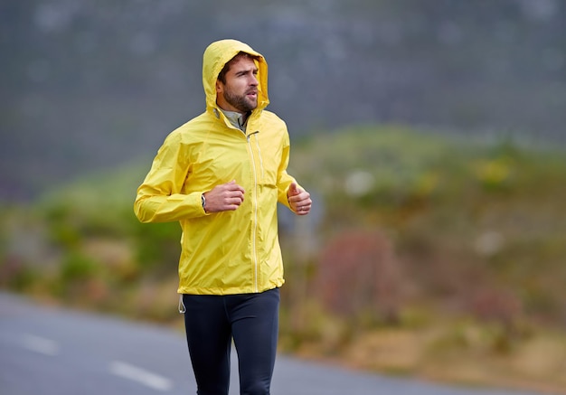 Sal ahí Toma de un apuesto joven corriendo en un clima lluvioso